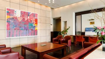 Una hall moderna con un'ampia pittura astratta, sedute in pelle e una reception.