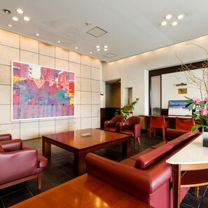 A modern lobby with a large abstract painting, leather seating, and a reception desk. - Fukuno Town Hotel Amieux (Nanto)