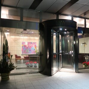A hotel entrance with a revolving door, a glass facade, and a colorful artwork on the wall. - Fukuno Town Hotel Amieux (Nanto)