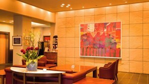 Un hall d’entrée avec une table ronde, des chaises rouges, un vase rempli de fleurs et une peinture abstraite aux couleurs vives accrochée au mur.