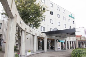A hotel with a modern design, featuring a covered entrance and a landscaped area with potted plants. - Fukuno Town Hotel Amieux (Nanto)