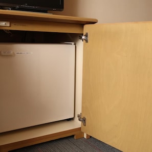 Ein geschlossener Holzschrank mit einem weißen Gerät darin, möglicherweise eine Mini-Kühlschrank oder Gefriertruhe.