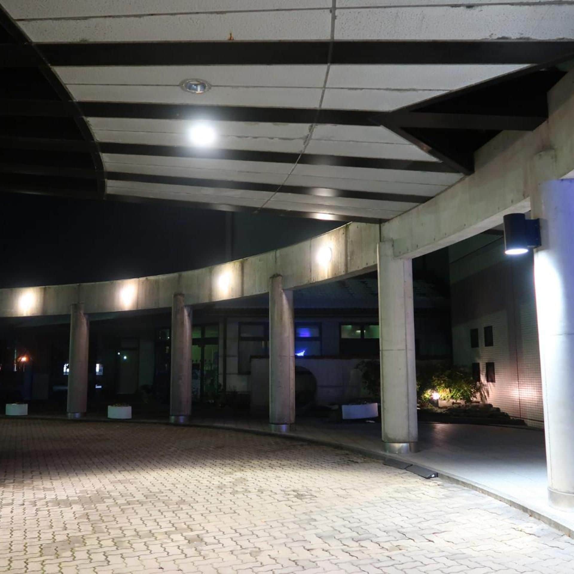 Un'area esterna coperta con colonne, pavimento in mattoni e un edificio sullo sfondo.