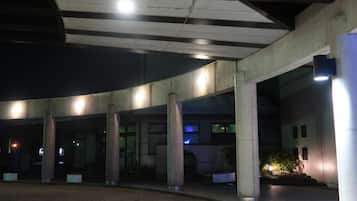 Un'area esterna coperta con colonne, pavimento in mattoni e un edificio sullo sfondo.