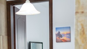 Een hal met een houten deur, een klein bureau met een spiegel, een kamerplant en een lijst met een foto aan de muur.