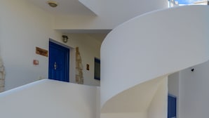 Een gebouw met meerdere verdiepingen, witte muren en blauwe deuren, met stenen accenten en een trap.