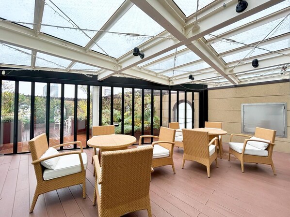 A covered patio area with wicker furniture and a view of the surrounding greenery. - Garden Hotel Shizuoka (Shizuoka)
