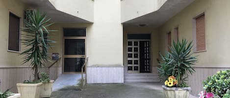 A courtyard with a central door, potted plants, and a concrete floor.