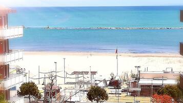 Un hotel sul lungomare con vista sul mare, una spiaggia sabbiosa e un molo.