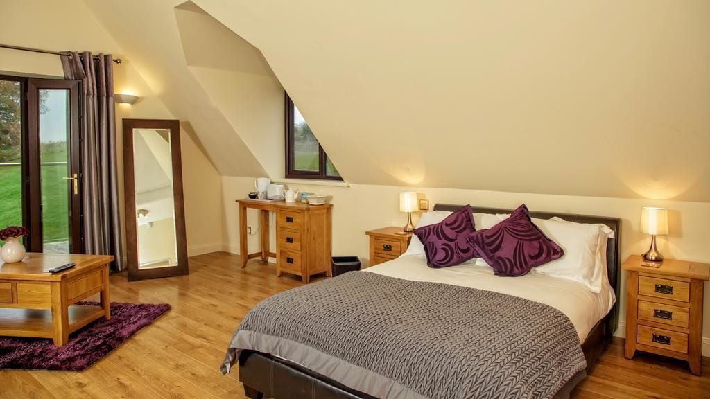 Une chambre à coucher avec un grand lit, des tables de chevet en bois, un bureau et un miroir.