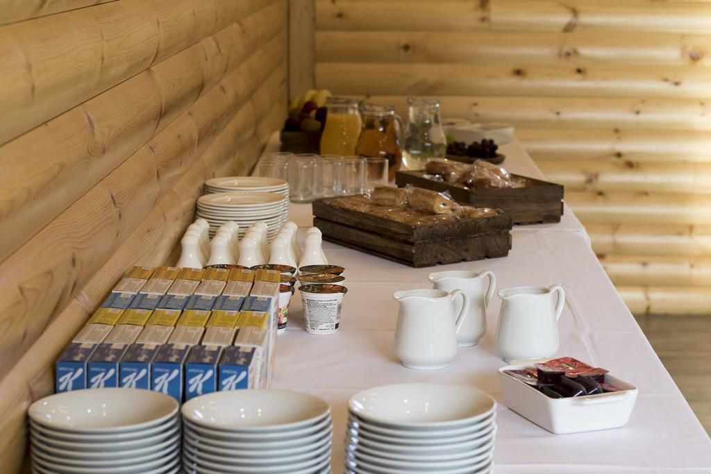 Un buffet de petit-déjeuner avec divers aliments, assiettes et ustensiles de service, le tout disposé sur une table dans une pièce en bois.