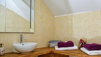 A bathroom with a white sink, a mirror, and a wooden vanity.