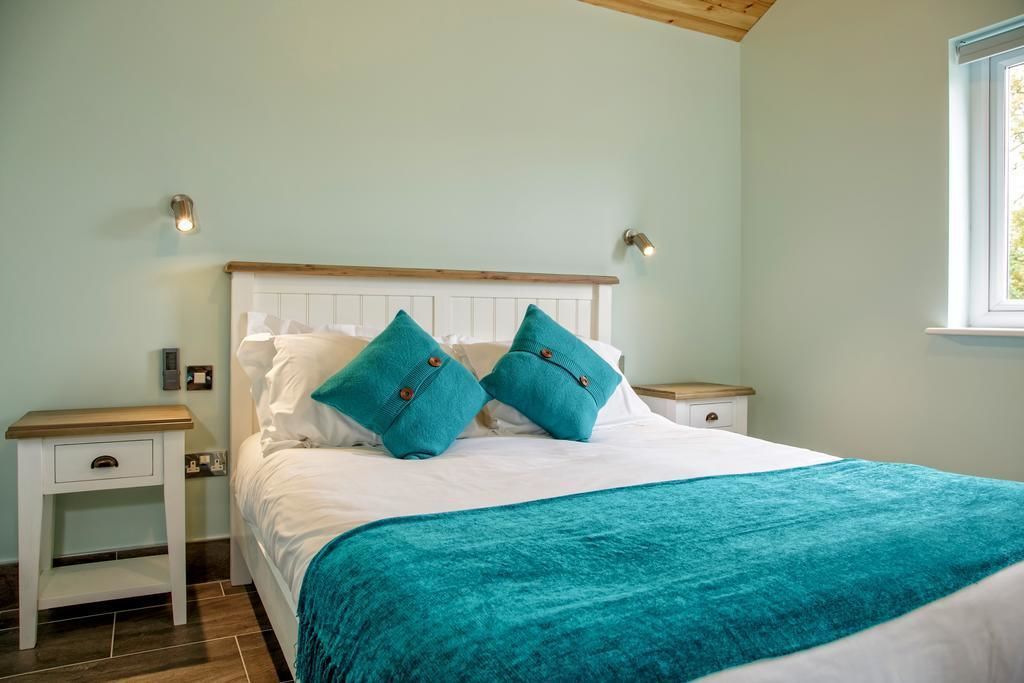 A bedroom with a bed, two nightstands, a window, and a teal throw blanket.