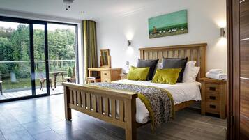 Een slaapkamer met een houten bed, een balkon met uitzicht op groen, een schilderij aan de muur en een plafondventilator.