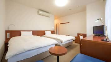 Habitación de hotel con dos camas, un escritorio con una computadora, un televisor y una pequeña mesa redonda.
