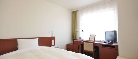 Una habitación de hotel con cama, escritorio, silla, televisor y ventana con cortinas.