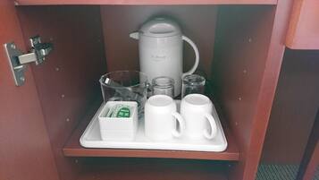 A breakfast tray with a teapot, glasses, and cups in a wooden cabinet.