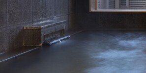 A stone wall with a small, rectangular, metal container on the floor. - Grand Park Hotel Odate (Odate)