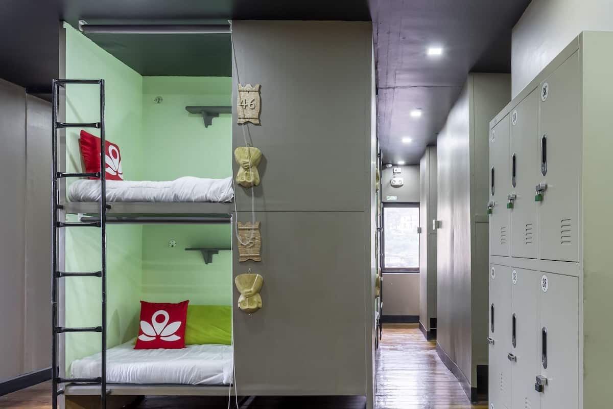 Un dormitorio con literas, una almohada roja, un teléfono y taquillas.