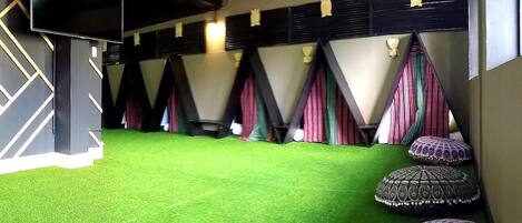 A room with a green carpet, a flat-screen TV, and a stage with curtains.