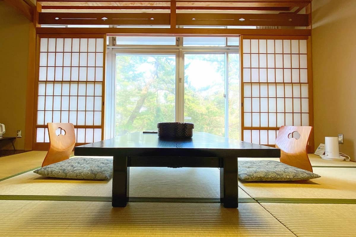 Une pièce de style japonais traditionnel, avec un sol recouvert de tatamis, une table basse et des paravents coulissants.