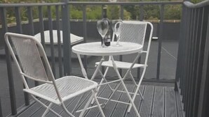 Una pequeña terraza al aire libre con una mesa redonda y dos sillas.