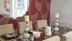 Un comedor con una mesa de madera, sillas color beige y un espejo decorativo.