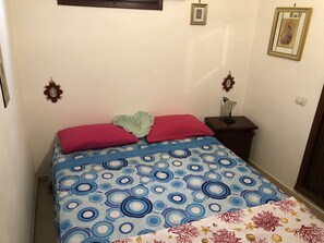 A bedroom with a bed, a nightstand, and a wall-mounted lamp.