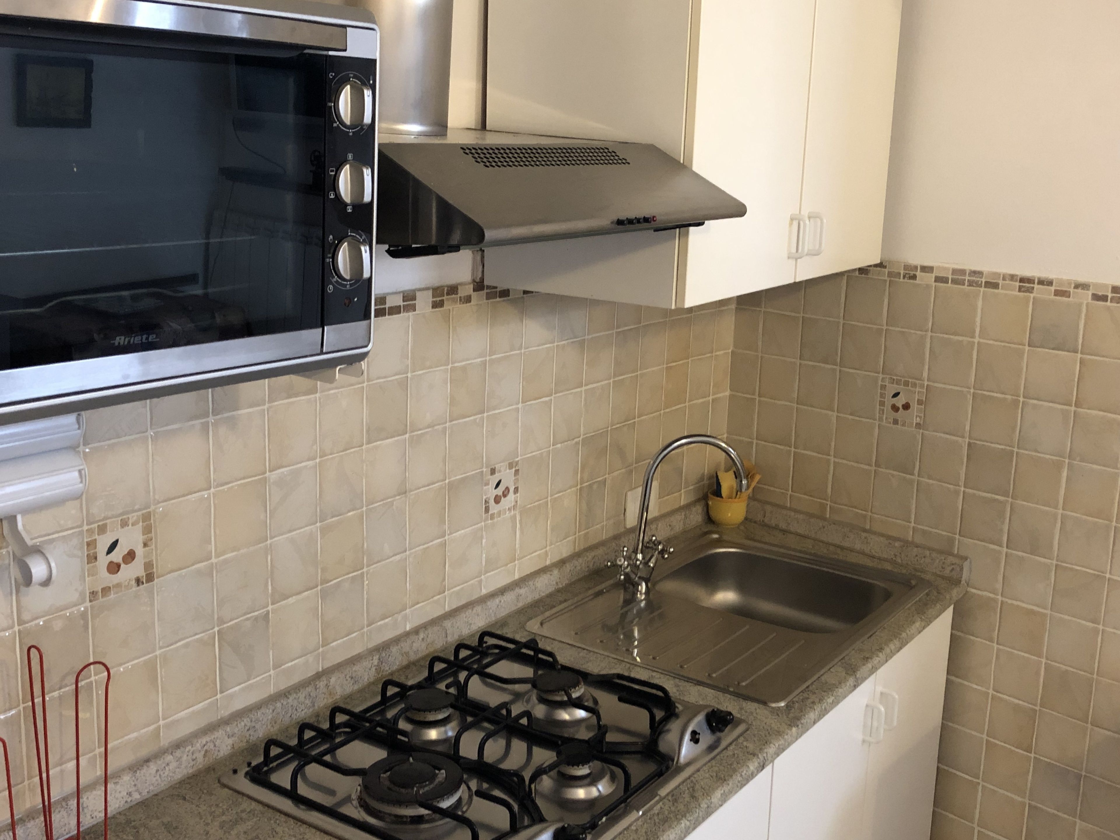 Una cucina con fornello, lavello e forno.
