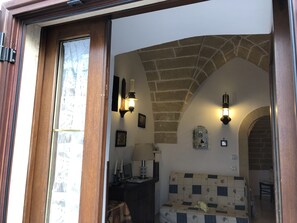 A room with a checkered sofa, a stone archway, and wall-mounted sconces.