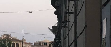 A street view with historical buildings, including a building with a balcony and a building with a dome.