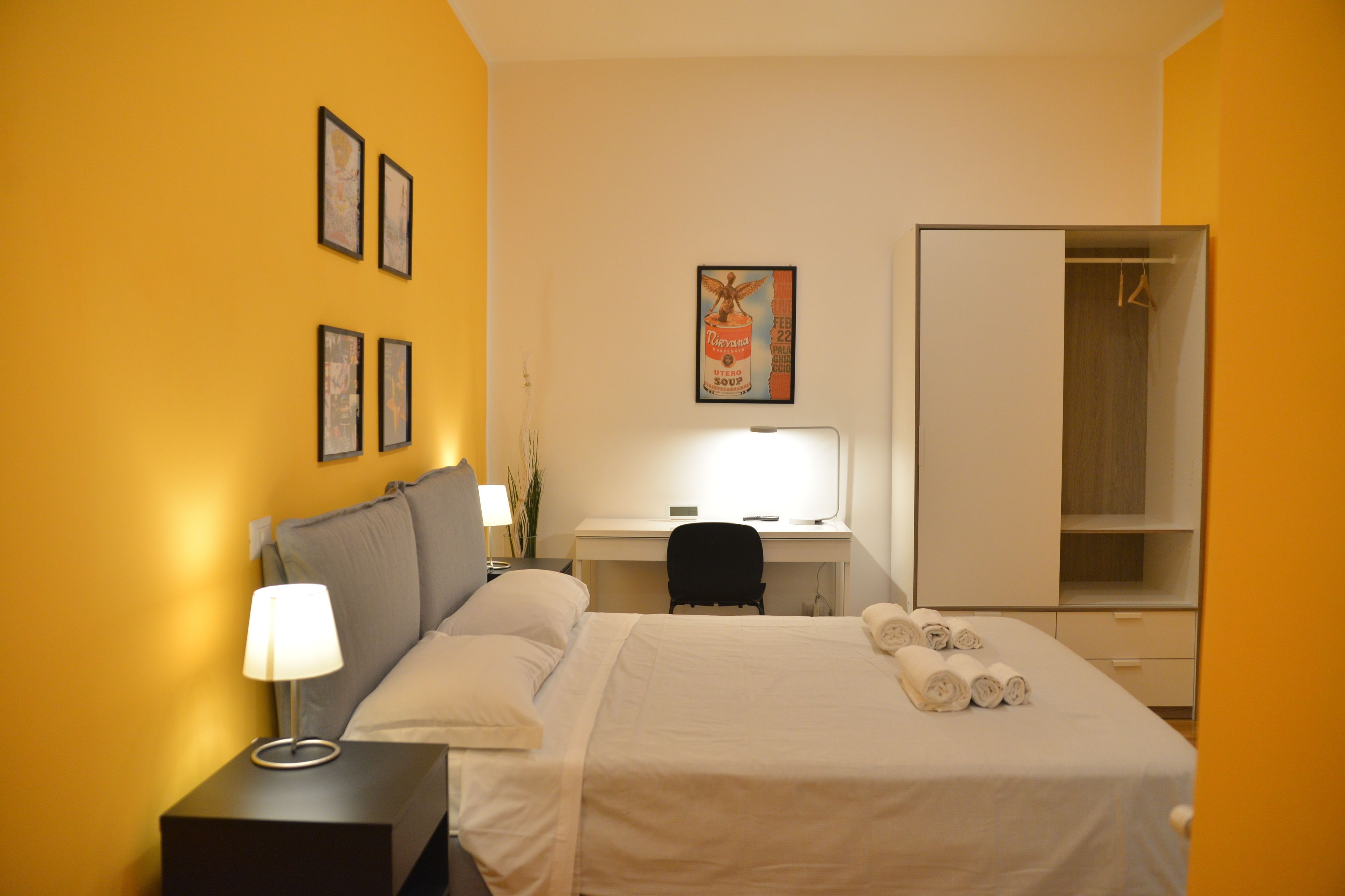 A hotel room with a bed, a desk, a chair, and a wardrobe.