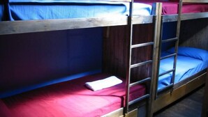 Een slaapkamer met een stapelbed, houten hoofdbord en rode beddengoed.