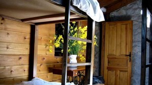 Une pièce de style cabane en bois, avec un lit, une étagère ornée de fleurs et une porte.