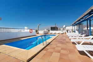 Una piscina al aire libre, sillones reclinables de piscina