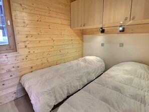 Una habitación pequeña con cama individual, paredes de madera y una ventana.