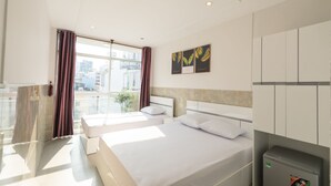 Een hotelkamer met twee bedden, uitzicht op de stad en een minibar.