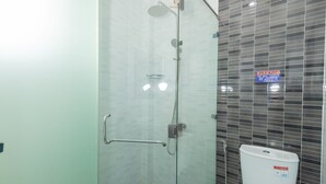 Une salle de bain moderne avec une douche à parois de verre, des toilettes blanches et un mur carrelé orné d’une inscription.