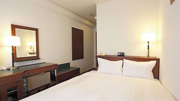 Een hotelkamer met een bed, een bureau met telefoon, een spiegel en twee bedlampjes.