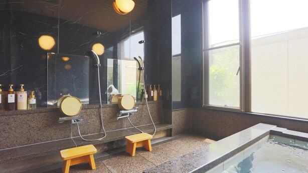 Ein modernes Badezimmer mit einem großen Spiegel, zwei hölzernen Hockstühlen, einer Duschkabine und einem kleinen Pool.