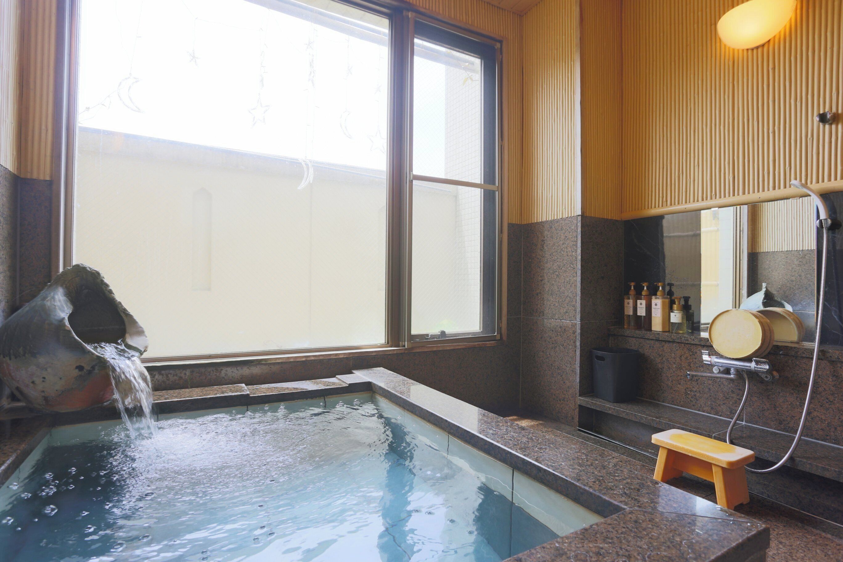 A spa area with a hot tub, a small wooden stool, and a shower.