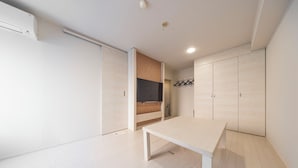 Una habitación moderna y minimalista con suelo de madera, una mesa blanca y armarios empotrados.