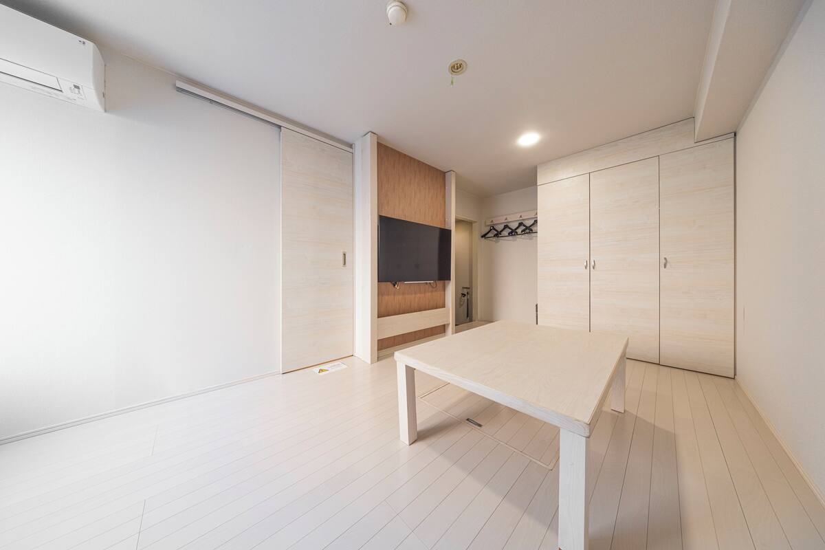 A modern, minimalist room with a wooden floor, a white table, and built-in wardrobes.
