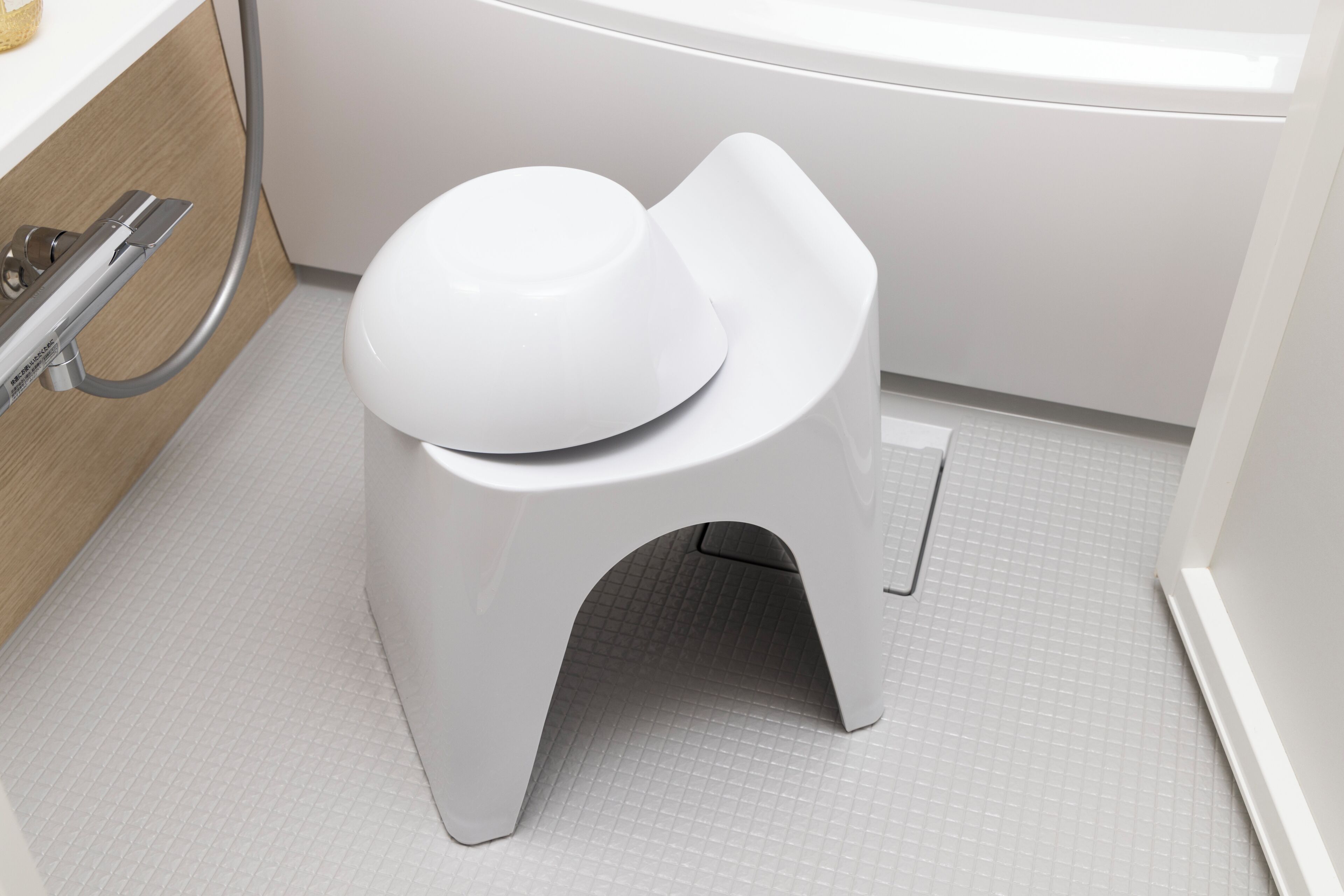 Une salle de bain moderne avec des toilettes blanches, une douche et un sol carrelé.