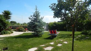 A well-maintained garden with a lawn, a pathway, and a chair. - S083 - Sirolo, new five-room apartment with garden (Sirolo)