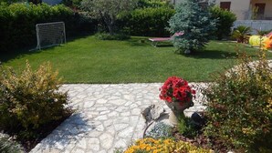 A stone patio with a flower pot, a grassy area with a goal, and a tree. - S083 - Sirolo, new five-room apartment with garden (Sirolo)