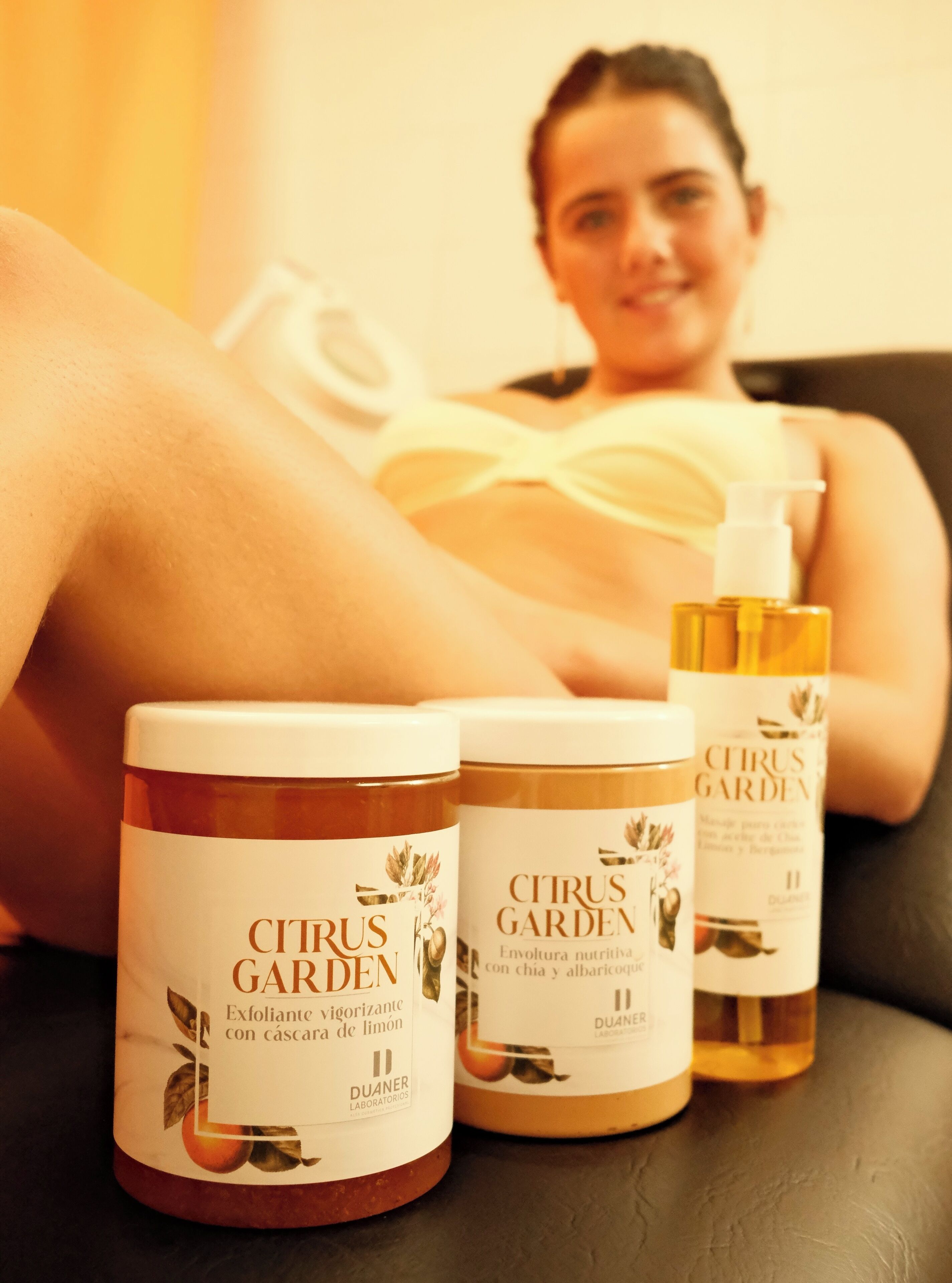 A person relaxing on a couch with three containers of Citrus Garden products in front of them.