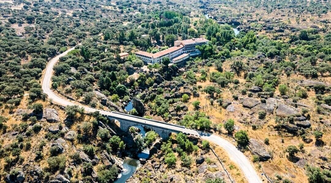 Vista aérea de un puente que conecta un edificio con un paisaje exuberante y verde.