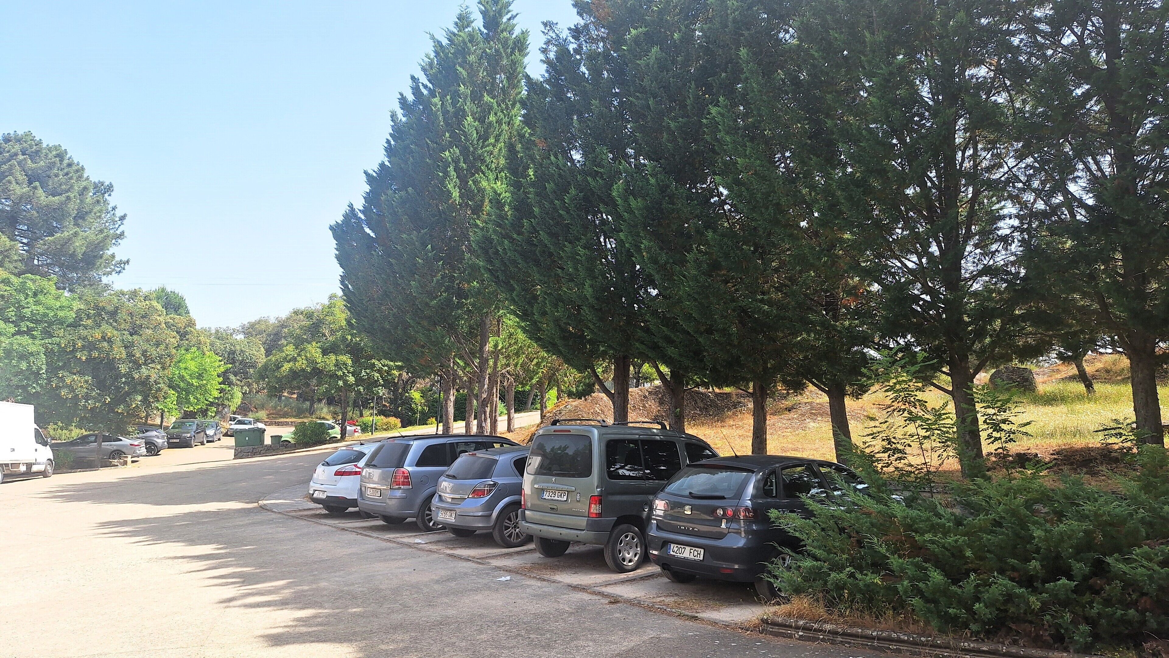A parking lot with several cars parked along the side of a road.