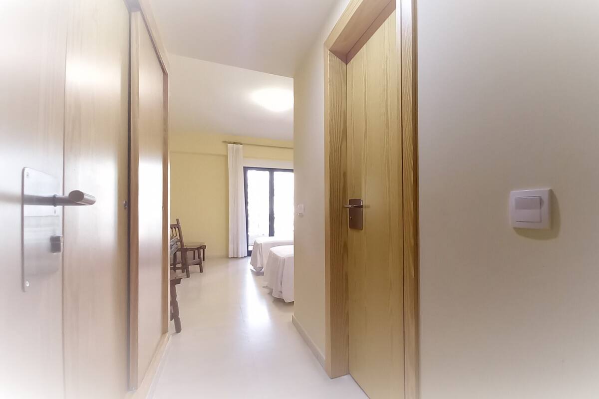 A hallway with wooden doors, a dining area with a table and chairs, and a window with curtains.